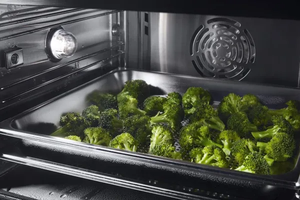A close-up of broccoli steaming inside the JennAir JJW6024HM steam oven 