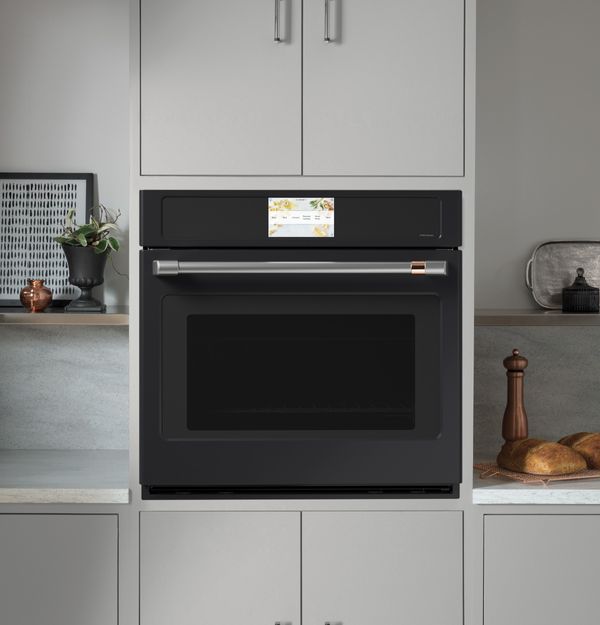 A Cafe matte black oven against teal cabinetry 