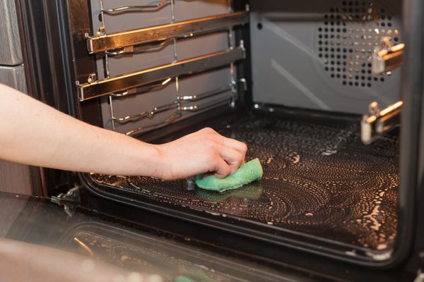 A person using a scrubber to clean an oven 
