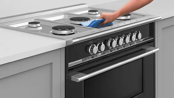 A person cleaning the Fisher & Paykel OR30SDG4X1 range