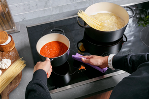 A person wiping down the GE Profile PHP9030STSS induction cooktop