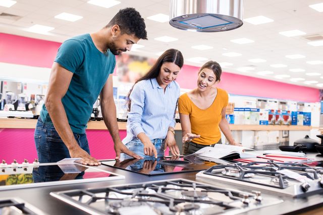 Front view of a couple with a saleswoman looking at an induction downdraft cooktop