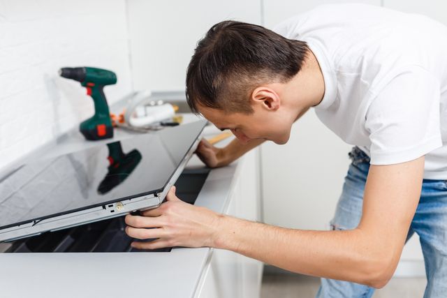 Side view of a man installing a cooktop