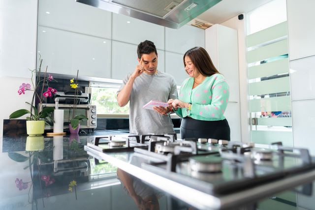 Front view of a couple looking at costs in front of a 36" gas cooktop in a modern kitchen