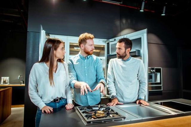 front view of a couple discussing cooktop options for an in-island range 