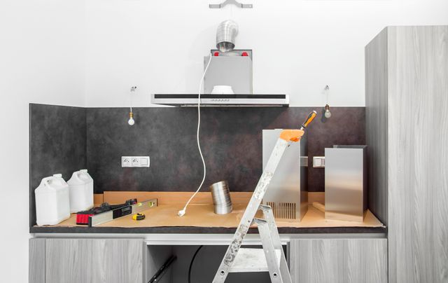 Front view of a modern kitchen renovation project with a ducted range hood being installed
