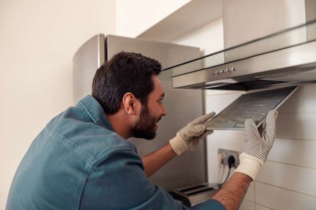 front view of a man completing a range hood installation