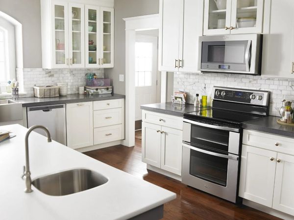 Kitchen with white cabinets as well as stainless steel double oven electric range and over the range microwave.