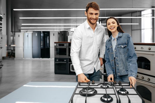 A couple smiling while reviewing a gas cooktop 