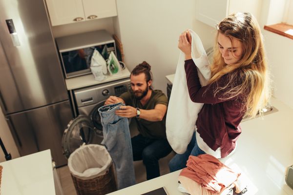 A man and a woman folding clothes in a small laundry room 