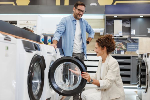 A man and a woman smiling while reviewing a front load washer