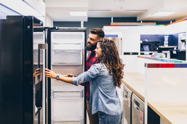 Front view of a couple shopping for a refrigerator in an applaince store