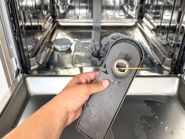 A close-up of a disassembled dishwasher spray arm