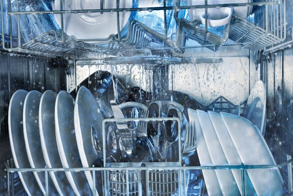 An internal view of dishes washing in a dishwasher 