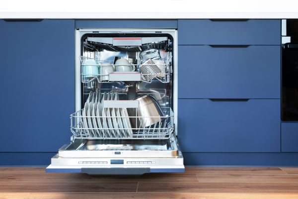 An open dishwasher in a blue kitchen 