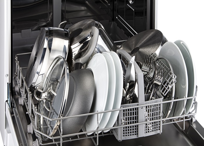 Bottom rack of a dishwasher filled with clean dishes and silverware. 