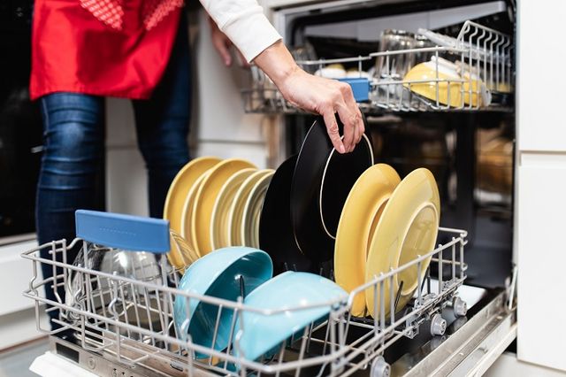 front view of a woman unloading a dishwasher full of dry dishes