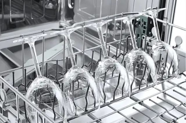 close view of five wine glasses in a dishwasher