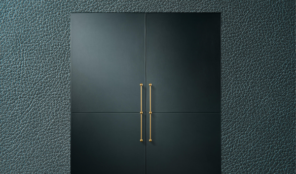 A pair of JennAir® Columns fitted with Mystic Cuts Leather Panels and custom handles on a background of the leather’s texture