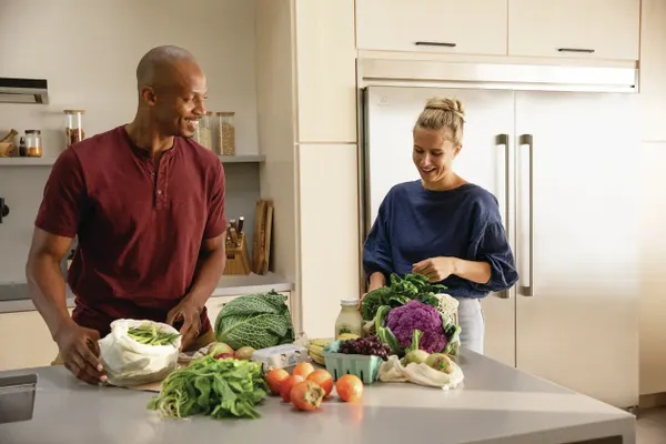 A man and woman preparing produce in front of Electrolux column refrigerators 