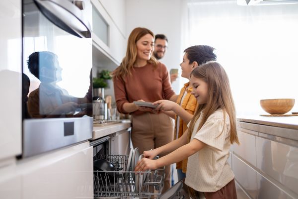 A family smiling while loading a dishwasher 