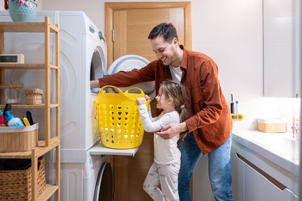 A father and a daughter unloading laundry from a stacked washer dryer
