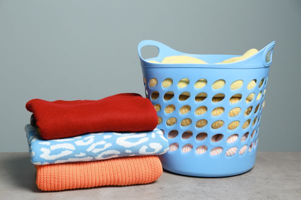 Folded clothes next a blue laundry basket filled with clothes 