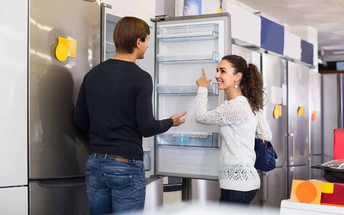 Couple choosing new refrigerator in appliance store.