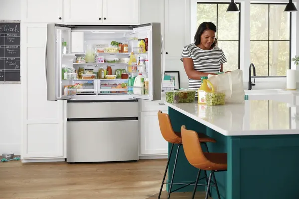 A woman unloading groceries with the Frigidaire Gallery GRMC2273CF refrigerator in the background 