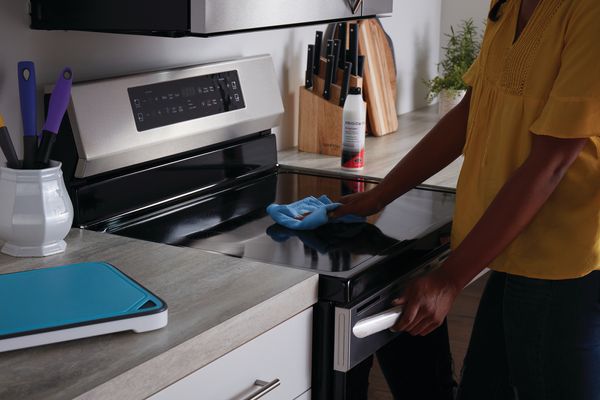 A person cleaning a Frigidaire electric range 