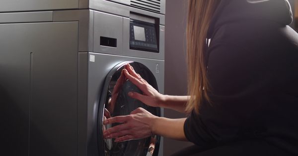 iStock Credit: Nimito A young woman using a front load washer