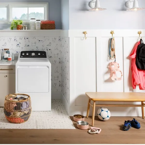 Credit: GE The GE GTD48GASWWB dryer in a laundry room with décor and clothes