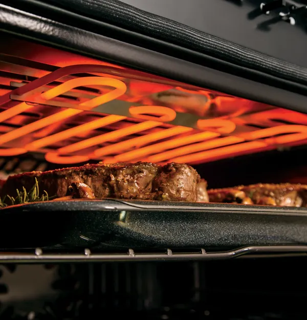 A close-up of the GE Profile PTS7000SNSS oven broiling steak