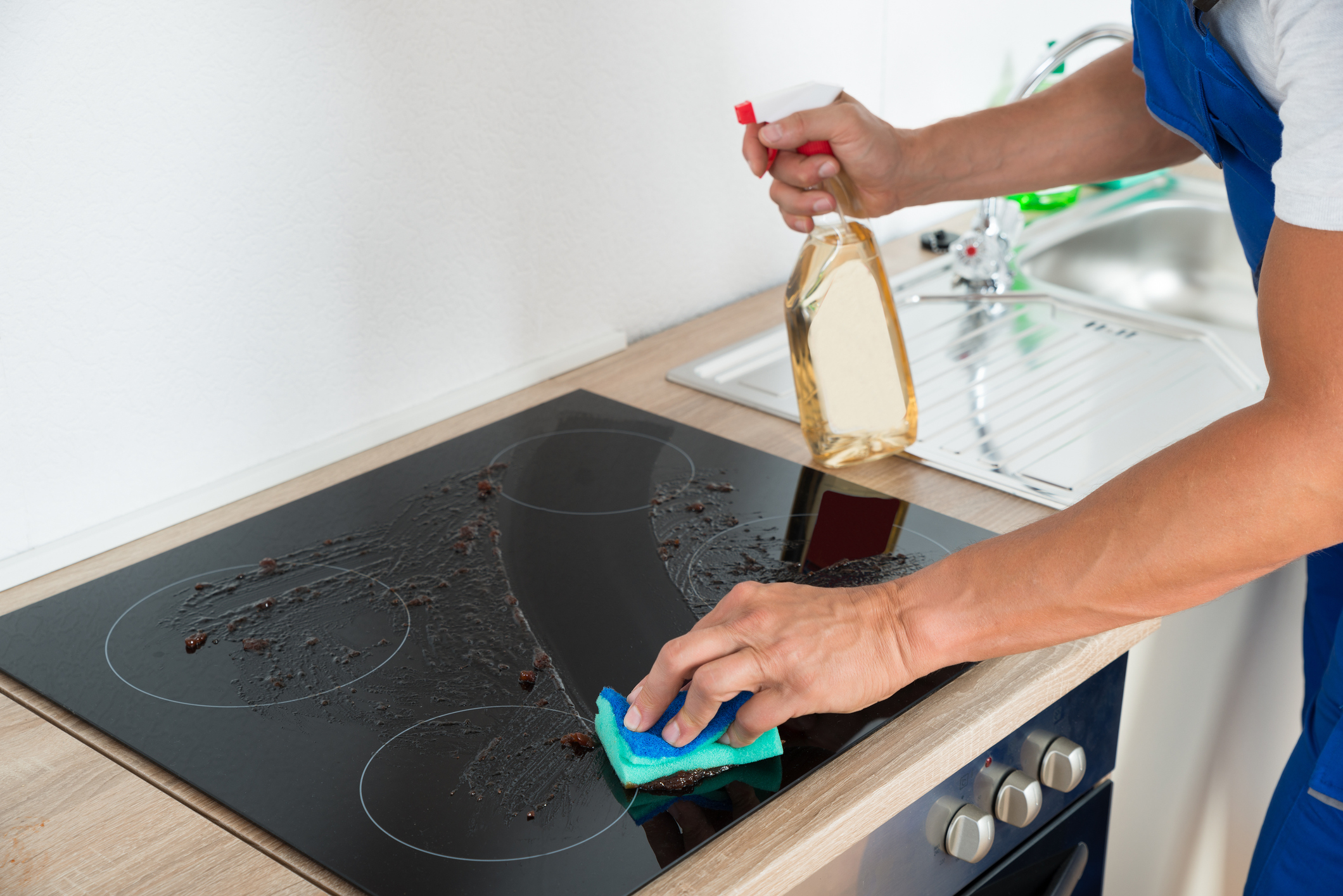 man cleaning grease and grime off induction range