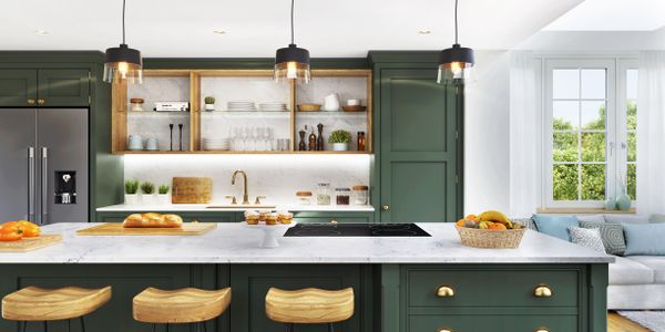 An open concept kitchen with green cabinets and gold hardware 