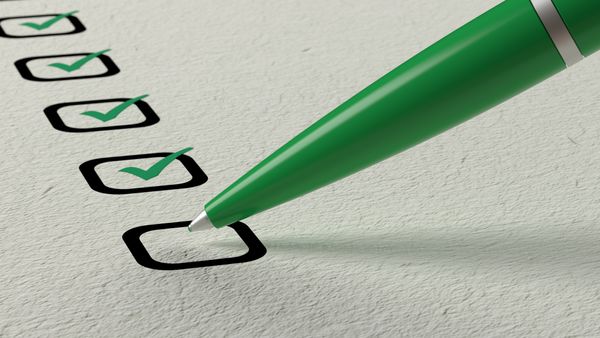A green pen marking green checks on a list