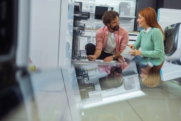 iStock Credit: Lajst A smiling man and woman review a dishwasher in a store