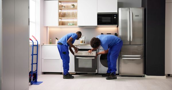 Two appliance technicians installing an oven 