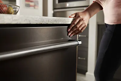 Credit: KitchenAid A close-up of a woman closing the KitchenAid KDTE204KBS dishwasher