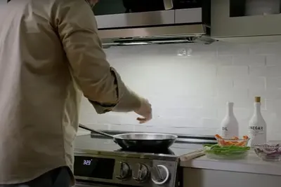 A person cooking on an LG range and with the LG MVEL2033F over the range microwave 