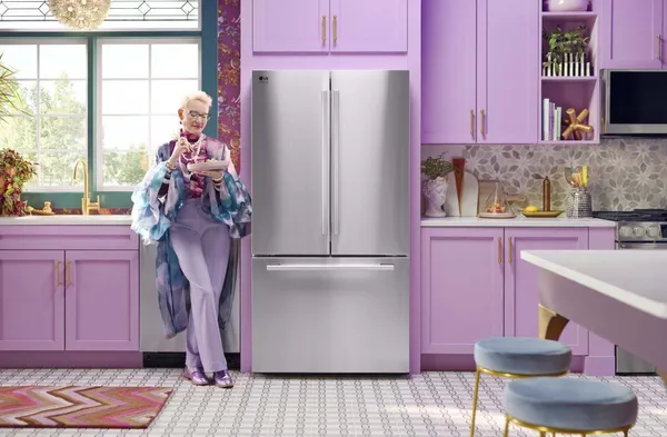 A woman in purple standing next to the LG Studio SRFB27S3 refrigerator in a purple kitchen