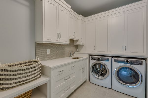 A laundry room with white cabinets and a matching washer and dryer