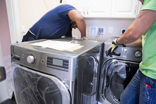 Front view of two men installing a washer and dryer in a laundry room