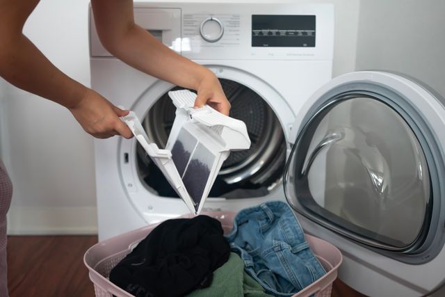 Credit: iStock Front view of a woman cleaning a front load washer filter