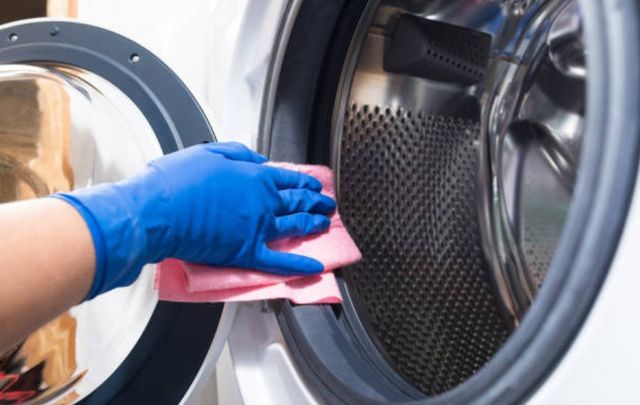 front view of a person cleaning a front load washing machine