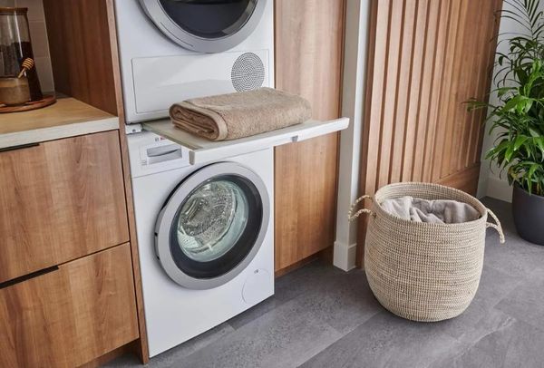 Stacked white Bosch front load washer and dryer installed in wood cabinets