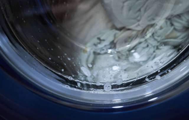close front view of a front load washer with white clothes indside