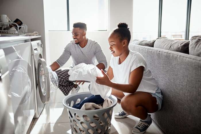 man and woman unloading laundry from washer dryer gas sets