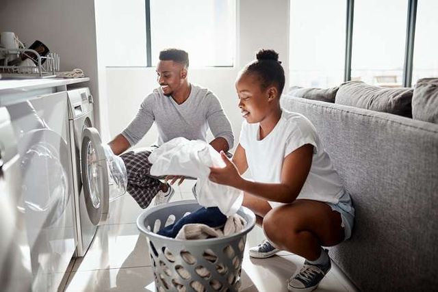 side view of a man and woman unloading clothes out of the dryer and smiling