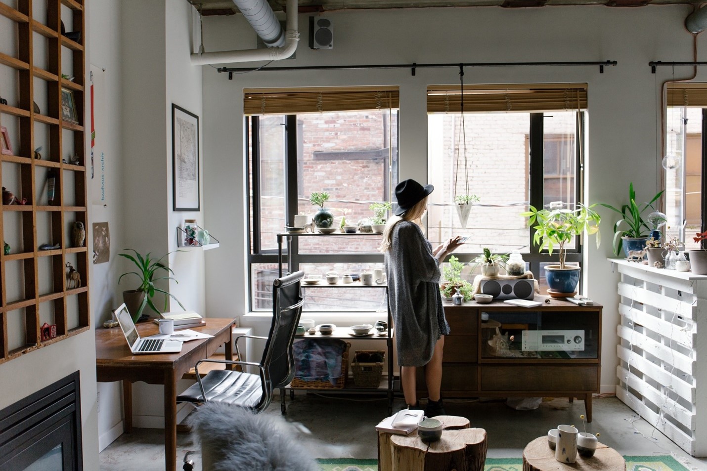 woman standing in a boho living space with desk and plants